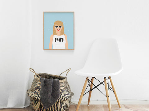 A white modern chair and woven basket sit by a wall showcasing the Onderkast Studio TS 1989 Art Print, featuring a woman with blonde hair, sunglasses, and 1989 shirt—an homage to Taylor Swifts iconic album art on light blue.
