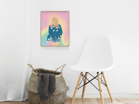 A white modern chair and woven basket sit in a minimalist room with the TS Lover Art Print by Onderkast Studio, a premium print featuring vibrant colors and a woman in a star-patterned jacket, hanging on the wall above them.