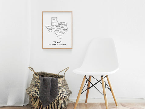 A minimalist room with a white chair, woven basket and blanket, plus the Texas Map Art Print by Onderkast Studio—an elegant Texas wall decor piece—displayed on a pristine white wall.