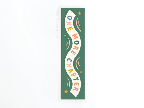 The One More Chapter Laminated Bookmark by Easyhand Goods features green laminate, colorful wavy ONE MORE CHAPTER text, small stars, and curved lines—perfect for avid readers.