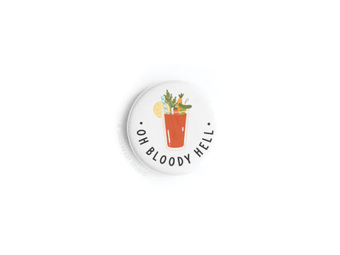 The Oh Bloody Hell Bloody Mary Button Magnet by Onderkast Studio features a Bloody Mary with garnishes and lemon slice on a crisp white background, plus the text “OH BLOODY HELL” underneath.