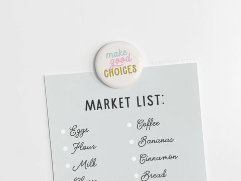 A paper grocery list—eggs, flour, milk, coffee, bananas, cinnamon, bread—is held in place by the vibrantly colored Make Good Choices Button Magnet from onderkast studio.