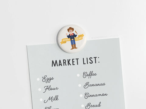 A market list, including eggs and coffee, is held by the Onderkast Studio Howdy Folks! Button Magnet featuring Big Tex on a white background, celebrating the State Fair of Texas.