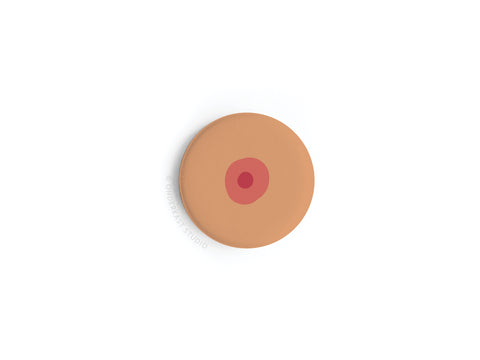 The Boob Button Magnet – Medium by Onderkast Studio is a light brown, round magnet with a central red circle, styled to resemble a nipple, shown on a white background for a playful body positive touch.
