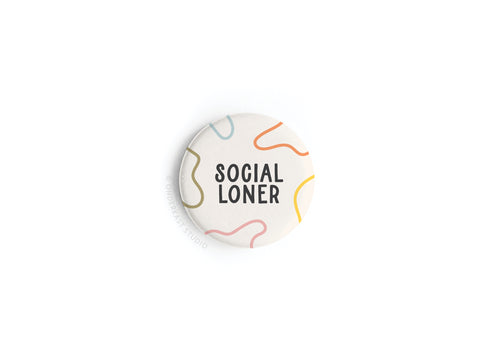 The Onderkast Studio Social Loner Button Magnet showcases bold black text with colorful squiggly lines, printed in the USA on a stylish round magnet.