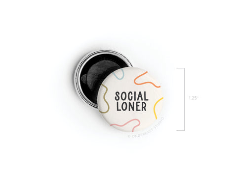 The Onderkast Studio Social Loner Button Magnet features bold black lettering with colorful squiggles on a 1.25 round design. Printed in the USA, it comes next to an open pin-back for style and versatility.