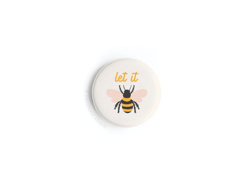 The Onderkast Studio Let It Bee Button Magnet is a round white magnet featuring a colorful honeybee illustration with “let it” in yellow text above the bee.