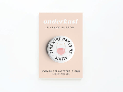 The Pink Wine Makes Me Slutty Pinback Button by Onderkast Studio features the fun quote around a glass of pink wine on a blush card—perfect for wine lovers. Displayed on the card: onderkast, PINBACK BUTTON, and ONDERKASTSTUDIO.COM.