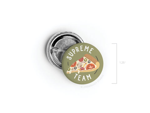 The Supreme Team Pizza Pinback Button by Onderkast Studio features a pizza slice illustration and text on a green background. Perfect for pizza fans, this round pin measures 1.25 in diameter.