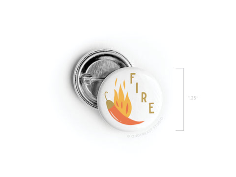 The Fire Chili Pinback Button by Onderkast Studio features a bold chili pepper, orange flames, FIRE printed vertically, and vibrant colors. This round button measures 1.25 inches in diameter.