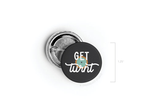 The Get Turnt Vinyl Pinback Button by Onderkast Studio is a 1.25 round pin featuring a black record design and the words GET turnt in playful white font, with turnt forming the tonearm—a fun accessory for music lovers.