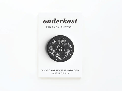 The discontinued Love Deeply Pinback Button from onderkast studio is a 1.25 round button with white floral designs and LOVE DEEPLY text, displayed on a branded onderkast PINBACK BUTTON card with contact info and MADE IN THE USA at the bottom.