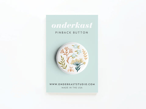 The Soft Florals Pinback Button by Onderkast Studio features a gentle floral design and comes on a pale blue card reading onderkast PINBACK BUTTON and www.onderkaststudio.com MADE IN THE USA.