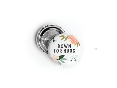 The Down For Hugs Pinback Button by Onderkast Studio is a 1.25-inch round button with eye-catching floral prints and bold text, shown face up and down, perfect for adding standout style wherever you pin it.