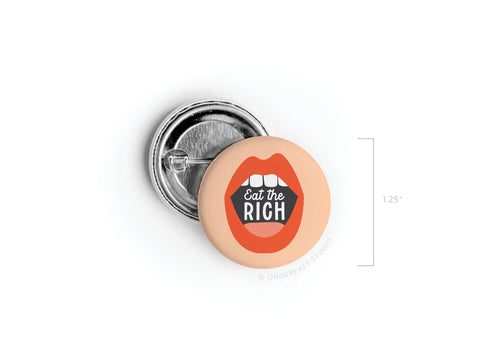 The Eat the Rich Pinback Button by Onderkast Studio features an open mouth with Eat the Rich inside, making a bold political statement. This 1.25-inch round button is displayed on a white background.