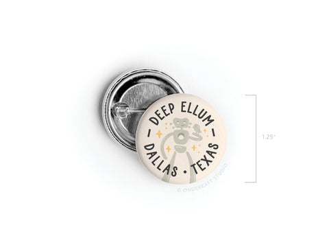 The Deep Ellum Travelling Man Pinback Button by Onderkast Studio features a vintage-style robot illustration with Deep Ellum Dallas Texas text. This round pin measures 1.25 inches in diameter.