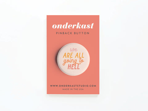 The We Are All Going to Hell Pinback Button by Onderkast Studio is a round button with orange and yellow text, displayed on a pink card reading onderkast pinback button, featuring the website and Made in the USA.