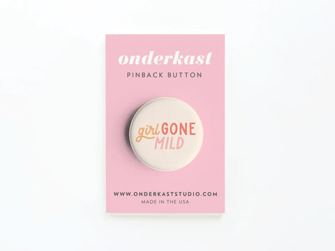The Girl Gone Mild Pinback Button by Onderkast Studio showcases bold pink and orange text on a pink backing card displaying “onderkast PINBACK BUTTON,” website, and “MADE IN THE USA,” all crafted with high-quality production.