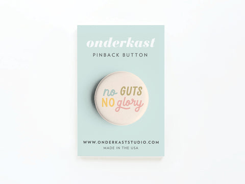 The No Guts No Glory Pinback Button by Onderkast Studio features no GUTS NO glory in pastel on a card labeled ONDERKAST PINBACK BUTTON, with www.onderkaststudio.com and MADE IN THE USA printed on it.