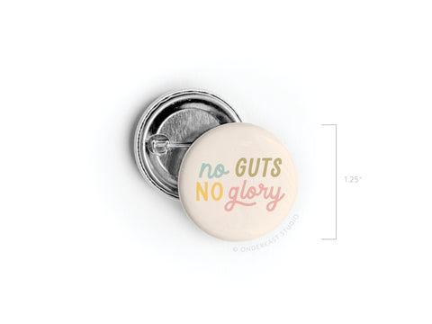 The Onderkast Studio No Guts No Glory Pinback Button features pastel “No Guts No Glory” text in blue, yellow, and pink on a cream background. Shown front and back, the round button measures 1.25 inches in diameter.