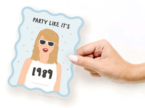 A hand holds the TS 1989 Wavy Die Cut Notecard by Onderkast Studio—a cartoon-style sticker of a blonde woman in sunglasses and a white tank, with PARTY LIKE ITS in bold above, perfect for showing your Swiftie charm.