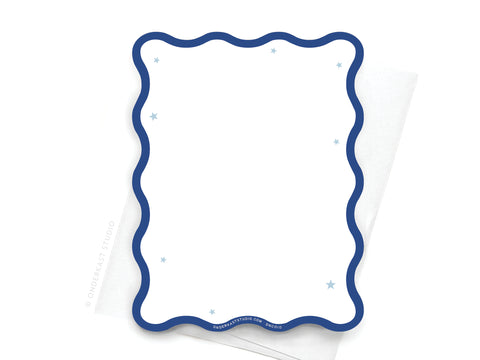 The Onderkast Studio TS Midnights Wavy Die Cut Notecard, inspired by Taylor Swift, features a blank card with a blue wavy border and stars atop a white envelope—perfect for any fan’s birthday.