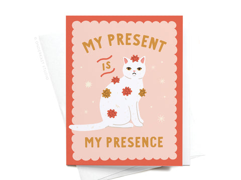 The My Present Is My Presence Cat Greeting Card by Onderkast Studio features a white cat with red and gold flowers, vibrant colors, and gold text on a pink scalloped border: My present is my presence.