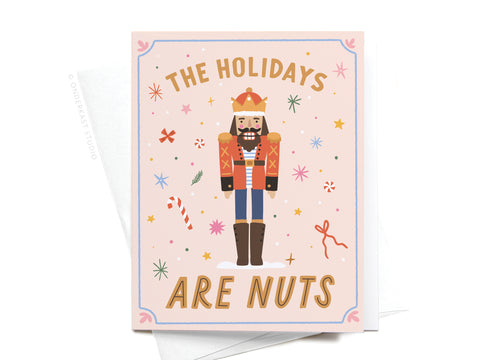 The Holidays Are Nuts Nutcracker Greeting Card by Onderkast Studio features a smiling nutcracker among candy canes, stars, and snowflakes. The card reads “THE HOLIDAYS ARE NUTS,” delivering a playful holiday greeting.