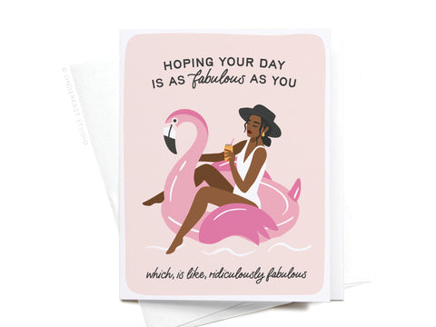 Fabulous Flamingo Floatie Greeting Card by Onderkast Studio features a woman in a sunhat and swimsuit relaxing on a pink floatie, drink in hand. Text: “Hoping your day is as fabulous as you, which is like, ridiculously fabulous.” Color: Dark.