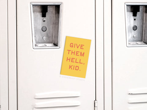 A vibrant yellow Give Them Hell Kid Refrigerator Magnet from Onderkast Studio, featuring bold red text and colorful design, is displayed on a white locker door among similar lockers.