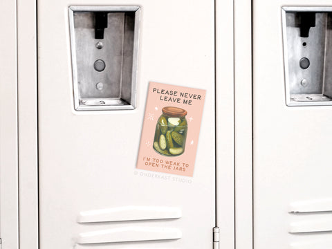 The Never Leave Me Pickles Jar Refrigerator Magnet by Onderkast Studio features a pink design with a jar of pickles and the text PLEASE NEVER LEAVE ME, IM TOO WEAK TO OPEN THE JARS—a quirky gift for pickle fans.