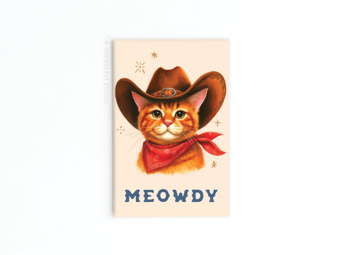 The Meowdy Cowboy Cat Refrigerator Magnet by Onderkast Studio features an illustrated orange cat in a brown cowboy hat and red bandana above “MEOWDY,” all on a beige background with decorative stars.