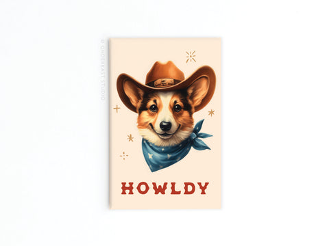 The Howldy Cowboy Dog Refrigerator Magnet by Onderkast Studio features a corgi in a cowboy hat and blue bandana, HOWLDY in bold red letters, and decorative stars for extra western charm on your fridge.