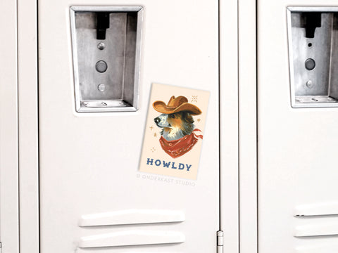 Add a touch of Western charm to your space with the Onderkast Studio Howldy Cowboy Dog Refrigerator Magnet, featuring a dog in a cowboy hat and red bandana with HOWLDY printed below.