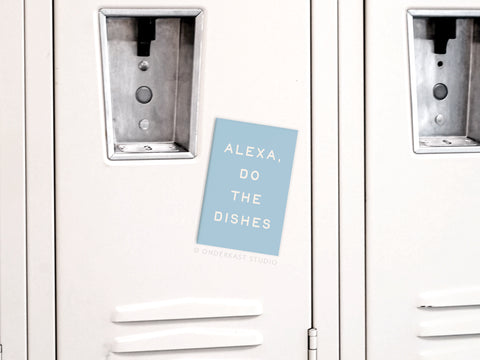 An Onderkast Studio Alexa Do the Dishes Refrigerator Magnet in light blue adds tech-inspired humor to a white locker’s plain metallic doors and handles.