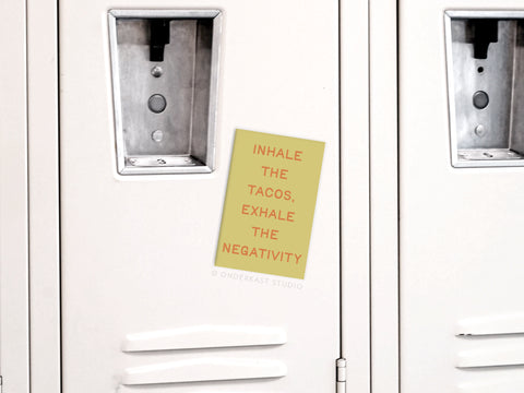 Add humor to your kitchen with the Onderkast Studio Inhale the Tacos Refrigerator Magnet—a beige locker-inspired magnet featuring a yellow note and red lettering: INHALE THE TACOS, EXHALE THE NEGATIVITY.