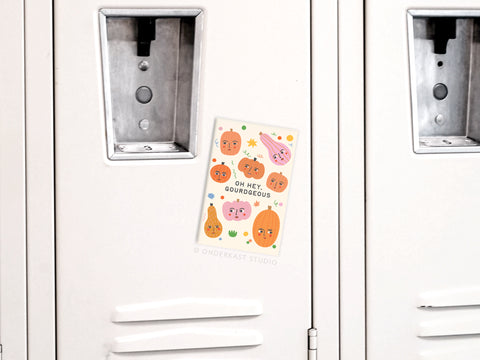 The Oh Hey Gourdgeous Refrigerator Magnet by Onderkast Studio decorates a locker door with its colorful illustrated fruits and cheerful greeting.