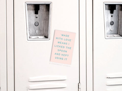 The Onderkast Studio “Licked the Spoon Refrigerator Magnet” features a colorful print on white, reading, “MADE WITH LOVE* MEANS I LICKED THE SPOON AND KEPT USING IT.” Perfect for any baking space or fridge!.