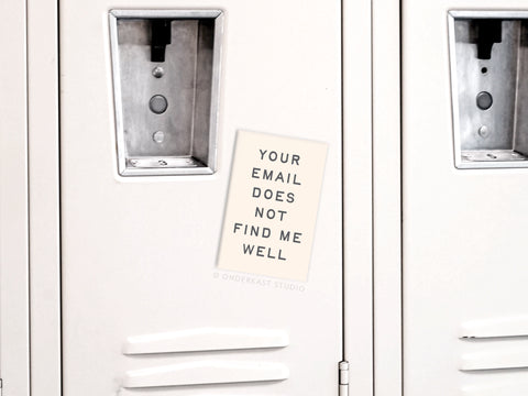 A beige locker displays the Onderkast Studio Your Email Does Not Find Me Well Refrigerator Magnet centered between metal doors—a fun digital detox reminder for any space.