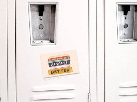A beige locker with Onderkast Studio’s The Book Is Always Better refrigerator magnet—perfect for book lovers—and a playful stacked-books illustration.