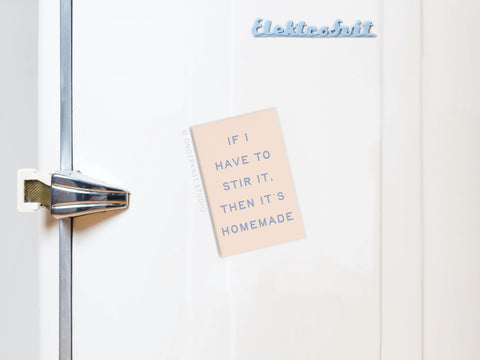 A white fridge with a silver handle displays an Onderkast Studio If I Stir It Then It’s Homemade Refrigerator Magnet, featuring the homemade-themed note and Elektrosvit written at the top.