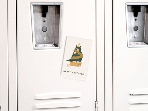 A Merry Whatever Cat Refrigerator Magnet by Onderkast Studio is attached to a white locker, adding festive cheer. The magnet features a cat and stands out against the visible locker doors and handles in the background.