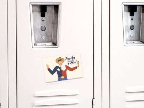 The Big Tex Refrigerator Magnet by Onderkast Studio features a cartoon cowboy in a Texas flag outfit holding a corndog and saying “Howdy Folks!”—a fun way to bring State Fair of Texas charm to your fridge or metal surface.