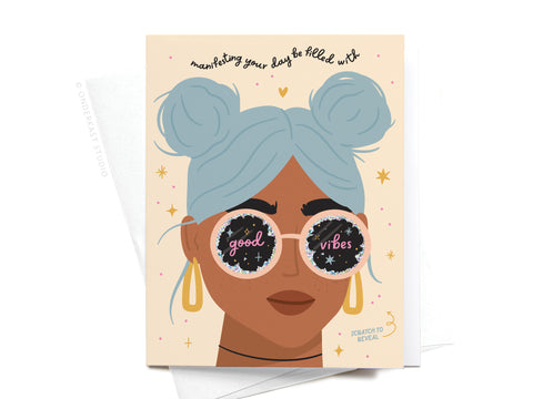 The Manifesting Good Vibes Scratch-Off Greeting Card by Onderkast Studio features a woman with light blue hair in buns, round good vibes sunglasses, and the phrase manifesting your days be filled with amid stars, hearts, and holographic glitter.