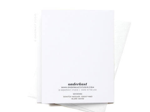 The Manifesting Good Vibes Scratch-Off Greeting Card by Onderkast Studio features a clean, mostly blank white design with subtle holographic glitter accents. Comes with a white envelope partially visible behind the card.
