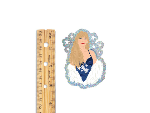 The TS Midnights Glitter Sticker by Onderkast Studio features a blonde woman in a blue, fur-trimmed dress with snowflake accents and a snowflake-shaped border. About 3 inches tall—perfect for any Swiftie!.