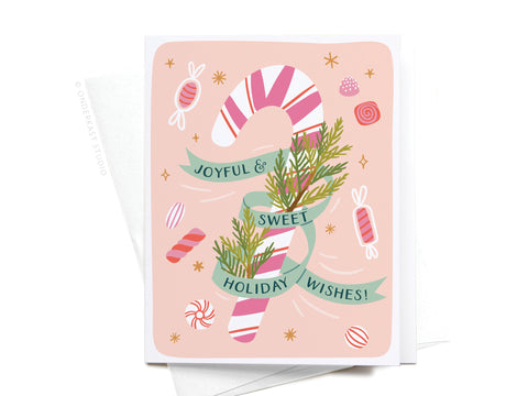 The Joyful & Sweet Holiday Wishes Candy Cane Greeting Card by Onderkast Studio features a pink and white candy cane with pine sprigs and a green Joyful & Sweet Holiday Wishes banner, surrounded by candies and stars on a peach background.
