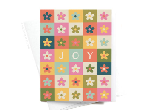 The Joy Daisies Greeting Card by Onderkast Studio features a premium feel and a grid of multicolored daisies, with three center squares spelling out JOY in white on orange, yellow, and pale pink backgrounds.