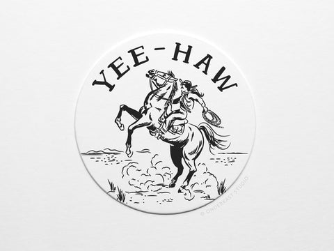 Onderkast Studios Yeehaw Cowgirl Coaster Set features a black and white illustration of a cowgirl riding a rearing horse with lasso and dust, under bold “YEE-HAW”—showcasing the handmade quality of letterpress coasters.