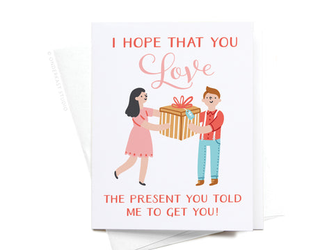 The Onderkast Studio I Hope You Love the Present You Told Me To Get You! Greeting Card features a light design with a smiling couple and fun pink/red text on premium cardstock.